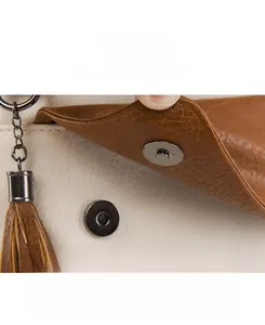 Detail of magnetic snap closure and tassel on pebbled leather backpack in beige and brown
