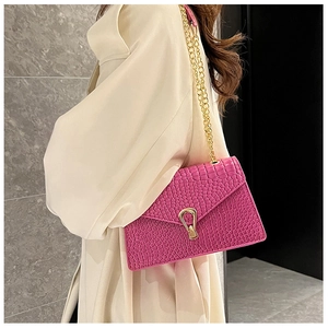 Detail of pink croc-embossed leather texture with golden horseshoe clasp on the bag