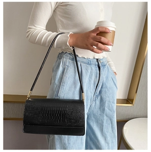 Close-up of black crocodile texture baguette bag with elegant golden hardware details