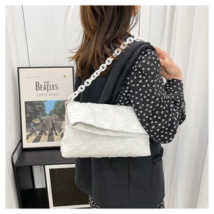 Macro shot of white checkered texture and thick chain strap on fashionable crossbody bag