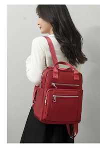 Detail of red waterproof nylon backpack showing multi-zipper pockets and top handles