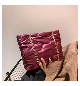 Detail of burgundy quilted puffer tote bag with glossy finish and gold chain strap