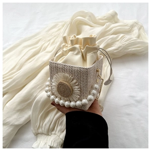 Detail of woven straw bucket bag with pearl handle and sunflower decoration
