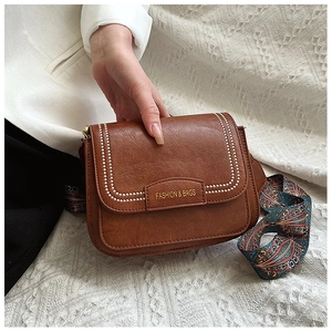 Dettaglio della borsa a tracolla marrone vintage con cuciture bianche e cinturino etnico