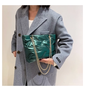 Detail of forest green quilted tote bag with V-shaped stitching and golden metal chain