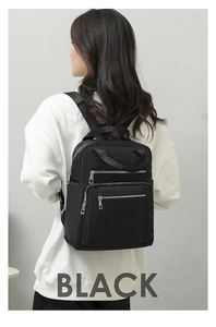 Close-up of black quilted backpack with silver zippers worn by a model in casual style