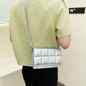 Fashionable silver quilted crossbody bag with sleek square design for women on a shoulder
