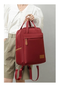 Detail of wine red waterproof nylon backpack with brown leather zipper and front pocket