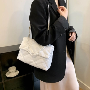 Sac bandoulière en nylon matelassé blanc avec grosse chaîne, porté par un mannequin en noir