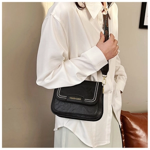 Dettaglio della borsa a tracolla in pelle nera con ampia tracolla jacquard e logo