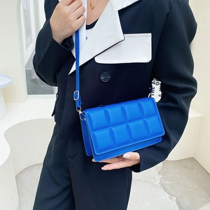 Klein blue quilted square crossbody bag with thin leather strap on model in suit
