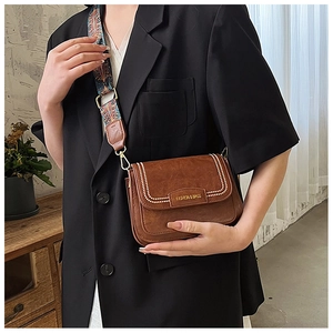 Dettaglio borsa a tracolla marrone vintage con cuciture bianche e tracolla intrecciata