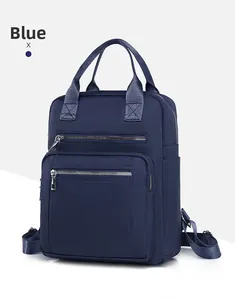 Detail of blue nylon backpack featuring multi-zipper front pockets and sturdy top handle