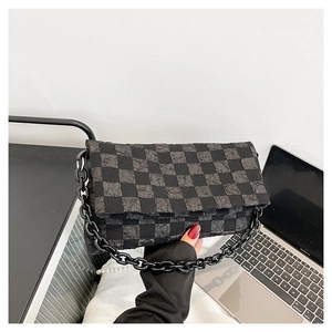 Detail of grey checkerboard bag with unique bubble texture and black chain strap