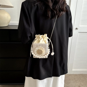 Woven straw bucket bag with sunflower detail and pearl handle worn as crossbody