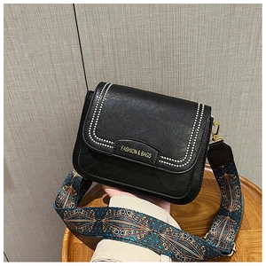 Dettaglio borsa a tracolla nera con tracolla etnica e borchie argentate decorative