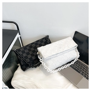 Detail of black and white crossbody bags with textured check patterns and resin chains