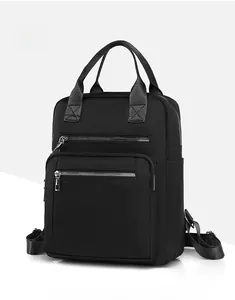 Detail of black quilted backpack with dual top handles and multi-zipper compartments