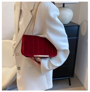 Vintage dark red velvet crossbody bag with gold chain strap shown on model in blazer