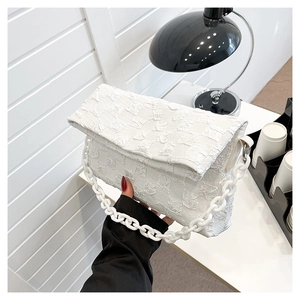 White checkered crossbody bag with thick chain strap shown in a hand-held detail view