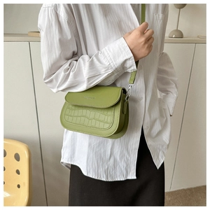 Dettaglio di una borsa a tracolla verde con goffratura a coccodrillo e design alla moda