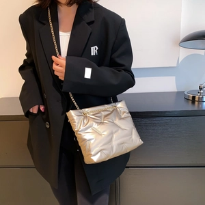 Champagne gold quilted chain tote bag worn with a black blazer for a stylish urban look