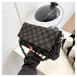 Detail of black bubble grid texture and chunky chain strap on a stylish crossbody bag