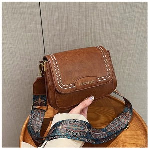 Dettaglio borsa vintage marrone con tracolla etnica boho e logo in rilievo di moda