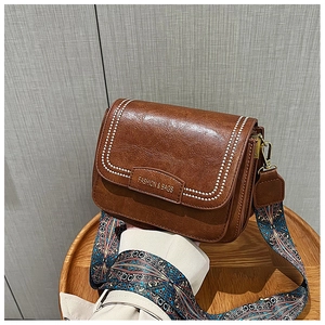 Dettaglio borsa quadrata in pelle PU marrone con cuciture ondulate e tracolla in tessuto