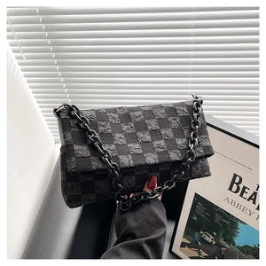 Detail of black checkerboard chain bag with unique puckered fabric and chunky resin chain