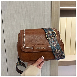 Dettaglio borsa quadrata vintage marrone con ampia tracolla a motivi geometrici