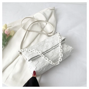 Detail of white quilted texture crossbody bag with thick chain strap decoration