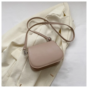 Dettaglio della borsa a tracolla rosa chiaro con fibbia argento su blazer beige