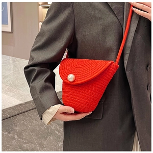 Detail of red hand-woven crossbody bag featuring a large pearl buckle on the flap