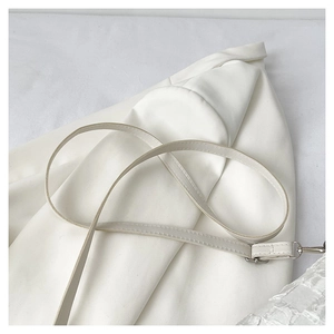 Detail of white PU leather strap stitching and silver metal buckle on a shoulder bag
