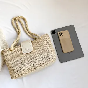 Comparaison de taille du sac en paille avec iPad et téléphone sur tissu blanc