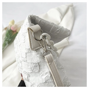 Detail of white bubble texture fabric and silver metal clasp on a stylish shoulder bag