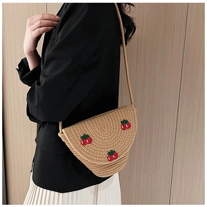 Detail of a straw woven crossbody bag with red cherry embroidery and a semicircular design