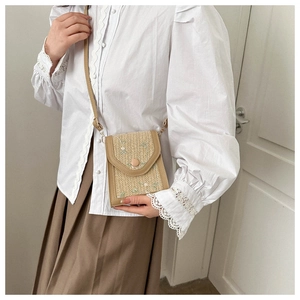 Detail of crossbody mini bag featuring straw texture and floral embroidery for women