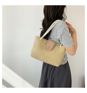 Vue détaillée d'un élégant sac cabas en paille tissé à la main porté à l'épaule par un mannequin