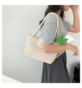 Détail du sac cabas en paille tissée avec poignées en corde et fermeture par rabat en cuir