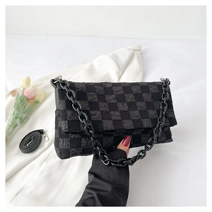 Detail of black checkered bubble fabric bag with acrylic chain and long strap