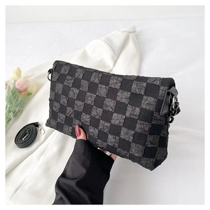 Close-up of black checkered crossbody bag with wrinkled fabric and metal rings