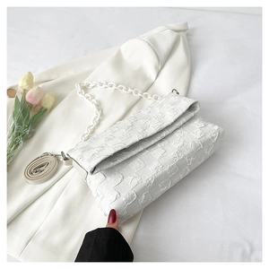 Detail of white pleated texture flap bag with plastic chain and leather strap