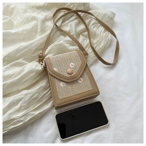 Close-up of woven mini straw bag with daisy embroidery and leather trim detailing