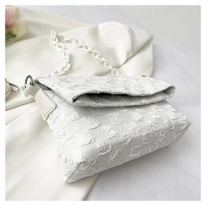 Detailed macro view of white waffle weave fabric and resin chain on crossbody bag