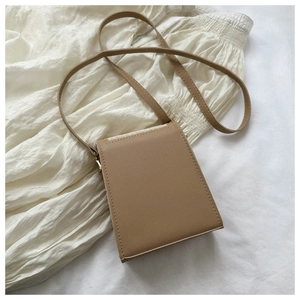 Detail shot of khaki PU leather mini crossbody bag with fine stitching on white fabric