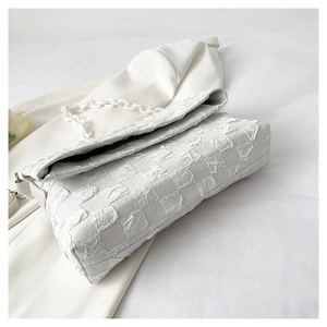 Detail of white checkered bubble texture handbag with chunky chain strap and metal clasp