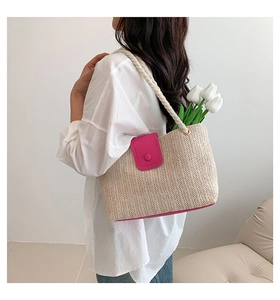 Détail d'un sac cabas en paille beige avec rabat en cuir rose vif et anse en corde de coton