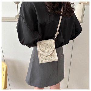 Detail of light beige woven crossbody bag with green floral embroidery and gold hardware